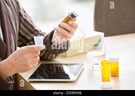 Älterer Mann, die Einnahme von Medikamenten am Tisch Stockfoto