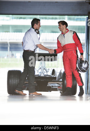 Racer und Manager Händeschütteln in garage Stockfoto