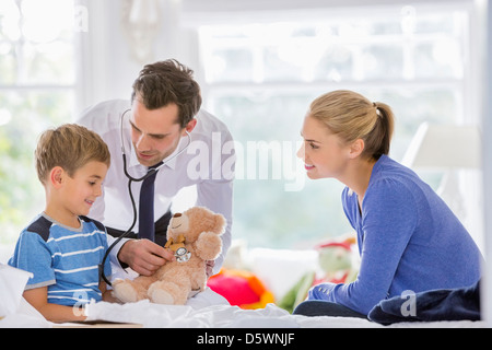 Arzt anhören Teddy Bär Herzschlag auf Hausbesuch Stockfoto