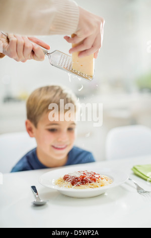 Mutter Gitter Käse über Sohnes spaghetti Stockfoto