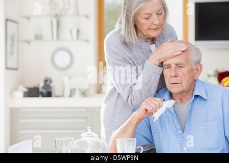 Ältere Frau Gefühl kranken Mannes Stirn Stockfoto