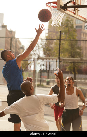Männer spielen Basketball auf Platz Stockfoto