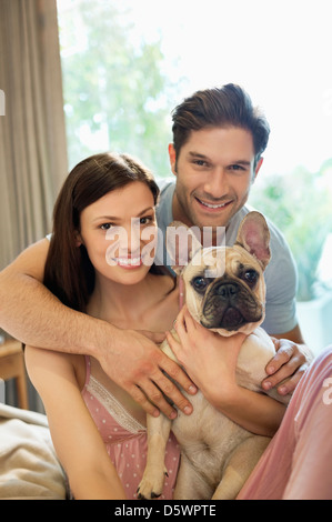 Paar umarmt Hund auf Bett Stockfoto