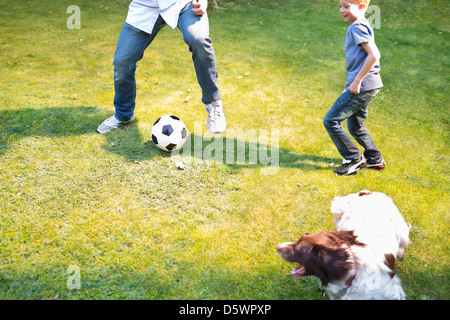 Jungen Fußball spielen mit Hund im freien Stockfoto