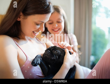 Mutter und Tochter Petting Hund im Bett Stockfoto