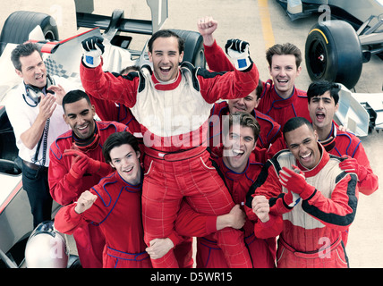 Racer und Team jubeln in garage Stockfoto