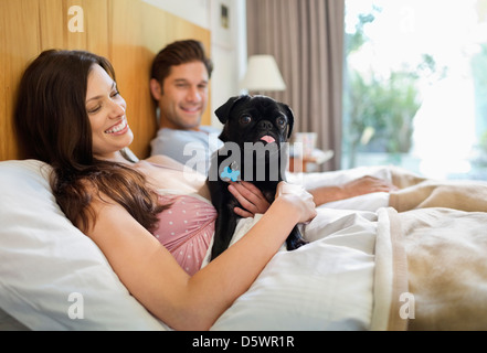 Paar mit Hund im Bett entspannen Stockfoto