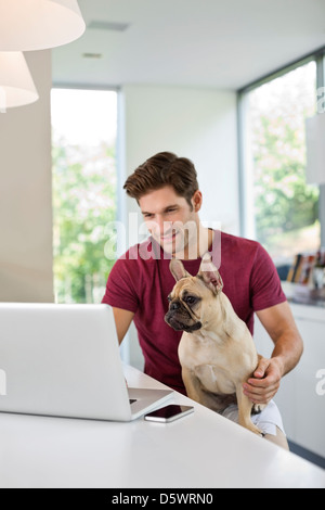 Mann mit Laptop mit Hund auf dem Schoß Stockfoto