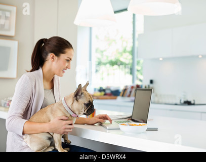 Frau mit Laptop mit Hund auf dem Schoß Stockfoto