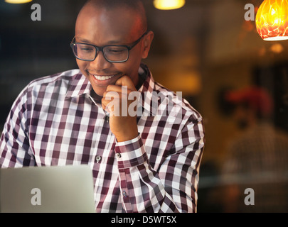 Lächelnd Mann Lesung Laptop im Haus Stockfoto