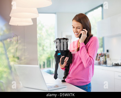 Frau am Handy halten Hund Stockfoto