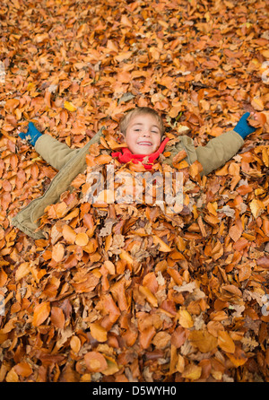 Junge im Herbstlaub Stockfoto