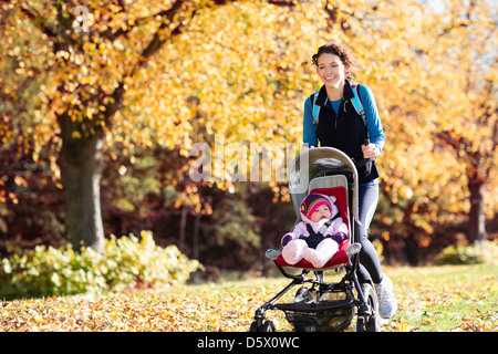 Frau mit Kinderwagen im Park läuft Stockfoto