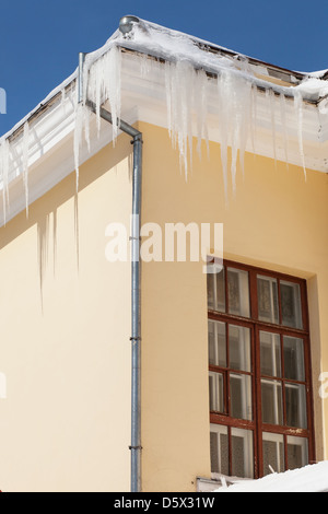Eiszapfen hängen von Regenrinnen an einem kalten Wintertag Stockfoto
