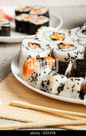Köstliche Sushi-Rollen mit Stäbchen Stockfoto