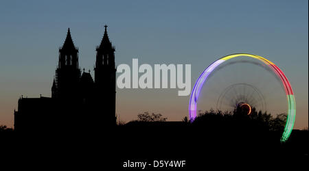 Ein Riesenrad, das mit Colorfull Lichtern beleuchtet wird, sieht man vor dem Dom "St. Katharina und Mauritius Sain" während der 1002. Herbstmesse statt in Magdeburg, Deutschland, 11. Oktober 2012. Menschen können auf die Herbstmesse bis 14. Oktober 2012 feiern. Foto: Jens Wolf Stockfoto