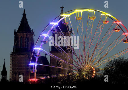 Ein Riesenrad, das mit Colorfull Lichtern beleuchtet wird, sieht man vor dem Dom "St. Katharina und Mauritius Sain" während der 1002. Herbstmesse statt in Magdeburg, Deutschland, 11. Oktober 2012. Menschen können auf die Herbstmesse bis 14. Oktober 2012 feiern. Foto: Jens Wolf Stockfoto