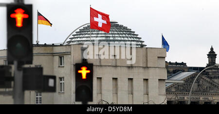 Eine Schweizer Flagge Wellen vor der Schweizer Botschaft in Berlin, Deutschland, 5. April 2012. Im Hintergrund sieht man die Kuppel des Reichstags. Eine geplante Steuerabkommen mit der Schweiz ist in der deutschen politischen Bereichen Ärger. Foto: WOLFGANG KUMM Stockfoto