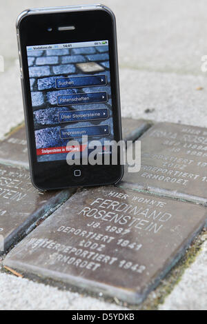 Abbildung - eine illustrierte Bild zeigt die neue app "Stolpersteinen in Hamburg" neben einem Stolperstein in Hamburg, Deutschland, 5. April 2012. Künstler Gunter Demnig erinnert seit 1995 die Opfer des NS-Regimes mit seinen "Stolpersteinen". Heute gibt es mehr als 32.000 kleine Gedenktafeln in mehr als 750 europäischen Städten. Um Bette können Stockfoto