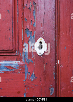 Schlüsselloch auf einer alten verfallenen roten Holztür Stockfoto
