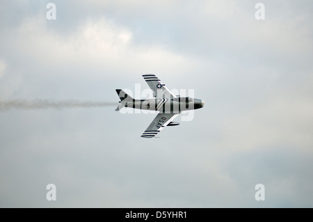 Ein 1950er Jahre amerikanische Kampfjet Flugzeug fliegt vorbei verlassen Rauchfahne, isoliert gegen einen grauen Himmel. Stockfoto