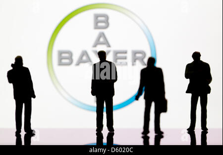 (ABBILDUNG) Eine Abbildung vom 9. November 2012 zeigt kleine Kunststoff-Figuren im Vordergrund des Logos der DAX-Unternehmen: Bayer in Berlin, Deutschland, 9. November 2012. Foto: Sven Hoppe Stockfoto