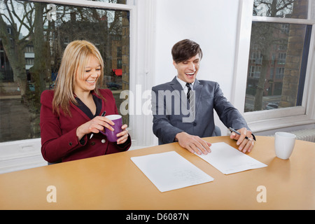Fröhliche junge Geschäftsleute mit Kaffee Tassen Dokumente t Konferenztisch Stockfoto
