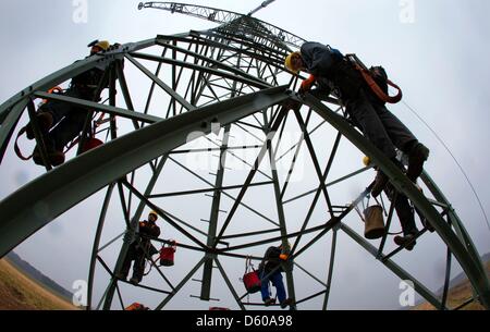 Menschen arbeiten an einer 110 kV-Freileitung zwischen Ludwigslust und Hagenow auf einem frisch installierten Pylon in der Nähe von Kummer, Deutschland, 10. April 2013. Der Energieversorger WEMAG derzeit modernisiert und verbessert die 19km lange Strecke von Stromleitungen und Pylone mit 9,4 Millionen Euro investiert. Foto: Jens Büttner Stockfoto