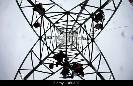 Menschen arbeiten an einer 110 kV-Freileitung zwischen Ludwigslust und Hagenow auf einem frisch installierten Pylon in der Nähe von Kummer, Deutschland, 10. April 2013. Der Energieversorger WEMAG derzeit modernisiert und verbessert die 19km lange Strecke von Stromleitungen und Pylone mit 9,4 Millionen Euro investiert. Foto: Jens Büttner Stockfoto