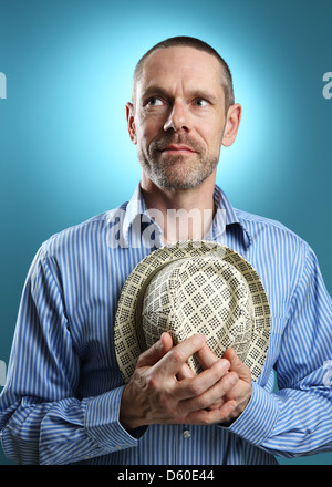 Porträt von einem reifen Erwachsenen halten eine Fedora und wegsehen von der Kamera mit einem sanften Lächeln. Stockfoto