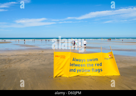 RNLI Life Guard Schild Warnung Schwimmer bleiben zwischen den Flaggen auf Westward Ho! Strand, Devon, England. Stockfoto