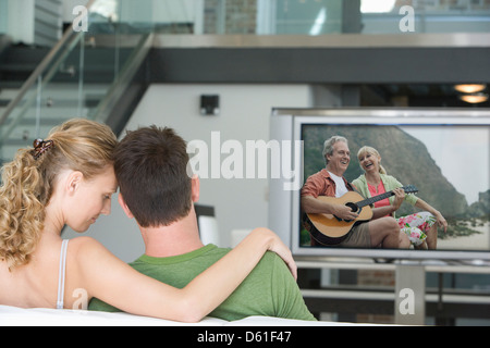 Rückansicht des jungen Paares vor dem Fernseher im Wohnzimmer Stockfoto