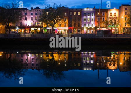 Horizontalen Blick auf die bunten Gebäude entlang Batchelors zu Fuß spiegelt sich in den Fluss Liffey in Dublin in der Nacht. Stockfoto