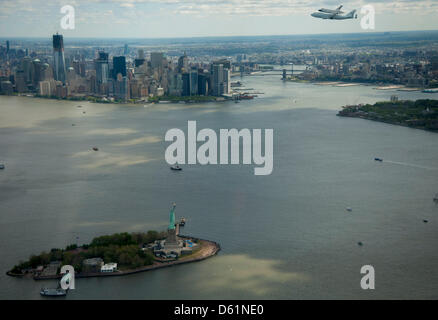 Space Shuttle Enterprise, montiert auf einer NASA 747 Shuttle Carrier Aircraft (SCA), wird gesehen, wie es in der Nähe der Freiheitsstatue und die Skyline von Manhattan, Freitag, 27. April 2012, in New York fliegt. Unternehmen war der erste Shuttle Orbiter gebaut für die NASA Testflüge in der Atmosphäre durchführen und war unfähig, Raumfahrt. Ursprünglich untergebracht an das Smithsonian Steven F. Udvar-Hazy Stockfoto