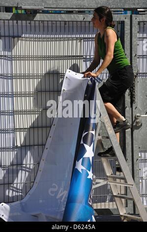 Eine Frau hängt ein blaues Schild mit der Aufschrift "UEFA Champions League - Finale 2012 München" im Eingangsbereich des Stadions für das Endspiel der Champions League in der Allianz Arena in München, Deutschland, 11. Mai 2012. FC Bayern München spielen FC Chelsea im Finale in München am 19. Mai 2012. Foto: Nicolas Armer Stockfoto