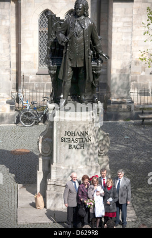 Tauf-Party posiert für Fotos vor der Statue des Komponisten J.s S. Bach im Innenhof des St. Thomas Church in Leipzig, Deutschland. Stockfoto