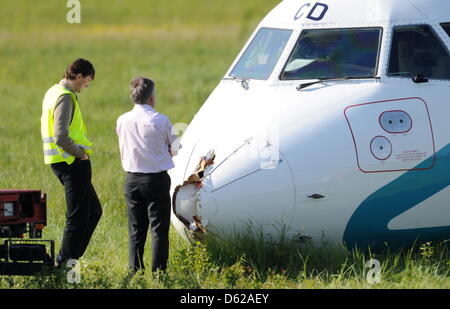 Zwei Männer Betrachten bin Donnerstag (17.05.2012) in München (Oberbayern) Ein Notgelandetes Flugzeug der Italienischen Fluggesellschaft Air Dolomiti, Das am Bug Beschädigt ist. Maschine Mit 62 Menschen sterben ein Bord Krieg Kurz Nach Dem Start in Richtung Venedig Umgedreht, Weil Sich Rauch in der Kabine Entwickelt wegdrücken. Bei der Landung Wurden Fünf Personen Leicht Verletzt, sterben Maschine Stockfoto