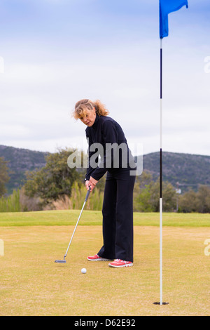 Frau mittleren Alters kaukasischen von 45 Jahren mit dem Putter auf einem Golfplatz Stockfoto