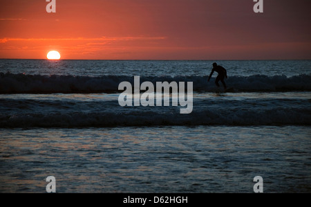 Ein einsamer Surfer bei Sonnenuntergang im Whitesands Bay, St. Davids Pembrokeshire Wales UK Stockfoto