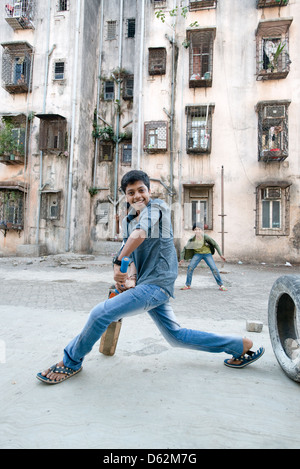 Ein Junge spielt Cricket durch einen Wohnblock in Mumbai, Maharashtra, India Stockfoto