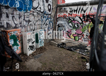 Wo junge deutsche einmal ihr Leben riskierten, schmücken Graffiti und Tags jetzt die Betonoberflächen der ursprünglichen Abschnitte der Berliner Mauer an der East Side Gallery auf Muhlenstrasse, Berlin. Die Website ist die ehemalige Grenze zwischen Ost und West Berlin während des Kalten Krieges. Die Berliner Mauer war eine Barriere, die von der Deutschen Demokratischen Republik (DDR, Ostdeutschland) ab dem 13. August 1961, gebaut, die völlig abgeschnitten (Landweg) West-Berliner aus den umliegenden Ostdeutschland und aus Ostberlin... (Mehr in Beschreibung). Stockfoto