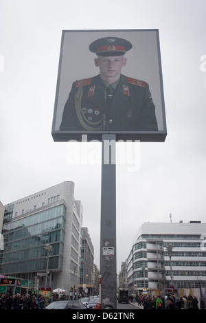 Das Porträt eines sowjetischen Soldaten sitzt hoch über dem modernen Friedrishstrasse in modernen Berlin am Standort des ehemaligen Checkpoint Charlie, die ehemalige Grenze zwischen Ost und West Berlin während des Kalten Krieges. Die Berliner Mauer war eine Barriere, die von der Deutschen Demokratischen Republik (DDR, Ostdeutschland) ab dem 13. August 1961, gebaut, die völlig abgeschnitten (Landweg) West-Berliner aus den umliegenden Ostdeutschland und aus Ostberlin. Stockfoto