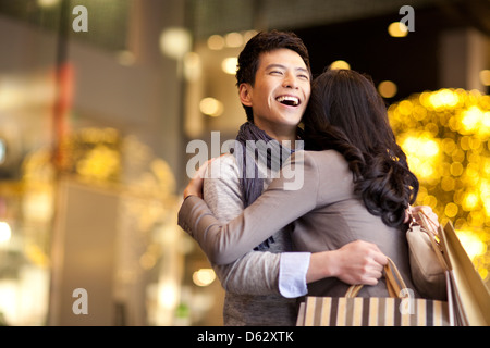 Süße junge Paar umarmt mit Einkaufstüten in Händen Stockfoto