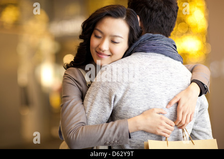 Süße junge Paar umarmt mit Einkaufstasche in Händen Stockfoto