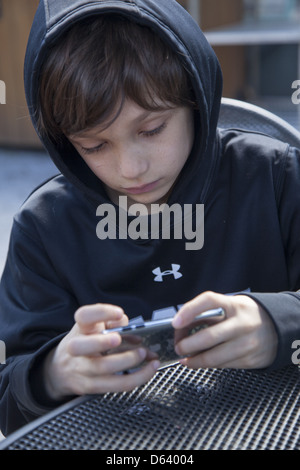 9 Jahre alter Junge spielt Minecraft auf seinem Ipod. Stockfoto