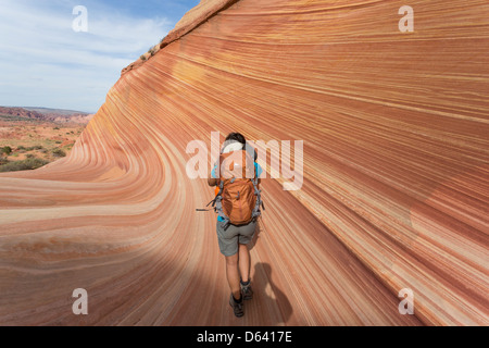 Junge Frau Wandern entlang der unmarkiert - The Wave - nahe der Grenze zu Arizona und Utah an den Hängen des Coyote Buttes Stockfoto