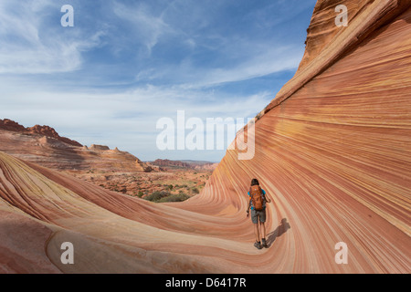 Junge Frau Wandern entlang der unmarkiert - The Wave - nahe der Grenze zu Arizona und Utah an den Hängen des Coyote Buttes Stockfoto