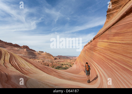 Junge Frau Wandern entlang der unmarkiert - The Wave - nahe der Grenze zu Arizona und Utah an den Hängen des Coyote Buttes Stockfoto