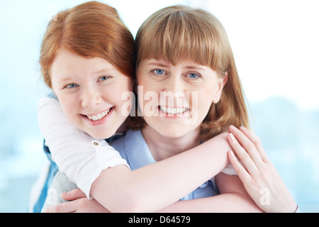 Schöne Mädchen und ihre Mutter mit einem Lächeln in die Kamera schauen Stockfoto