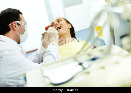 Junge Frau sitzt im Zahnarztstuhl beim Arzt untersuchen ihre Zähne Stockfoto